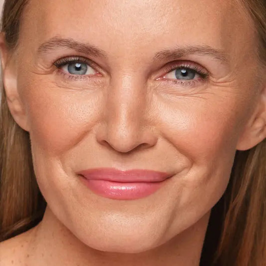 pH-adjusting lip gloss on smiling woman with soft pink tint and natural finish.