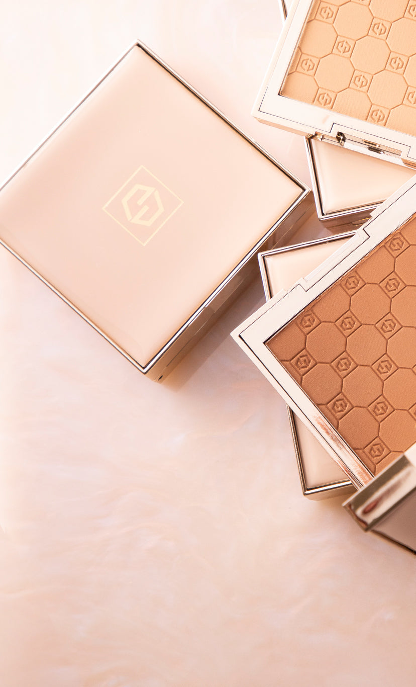Flat lay of Jouer Cosmetics' Soft focus pressed powders in luxe, gold-trimmed compacts, featuring a geometric embossed pattern on the powder surface.