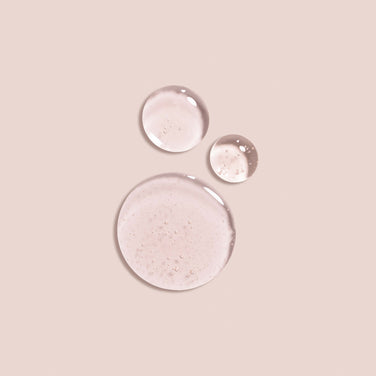 Side-by-side comparison of a woman’s face before and after makeup application. The "Before" image shows natural lips, while the "After" image displays glossy lips thanks to Jouer Cosmetics Essential Lip Oil and enhanced cheekbones, highlighting a subtle, paraben-free makeup look that accentuates her features.