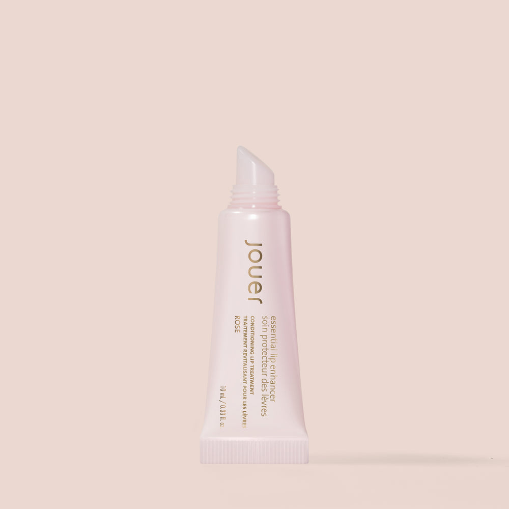 A rose-colored tube of Jouer Cosmetics Essential Lip Enhancer, expertly crafted to condition and plump lips. This gluten-free, paraben-free formula is housed in a soft, squeezable tube with a slanted applicator tip, adorned with gold and white text displaying the product name and description.