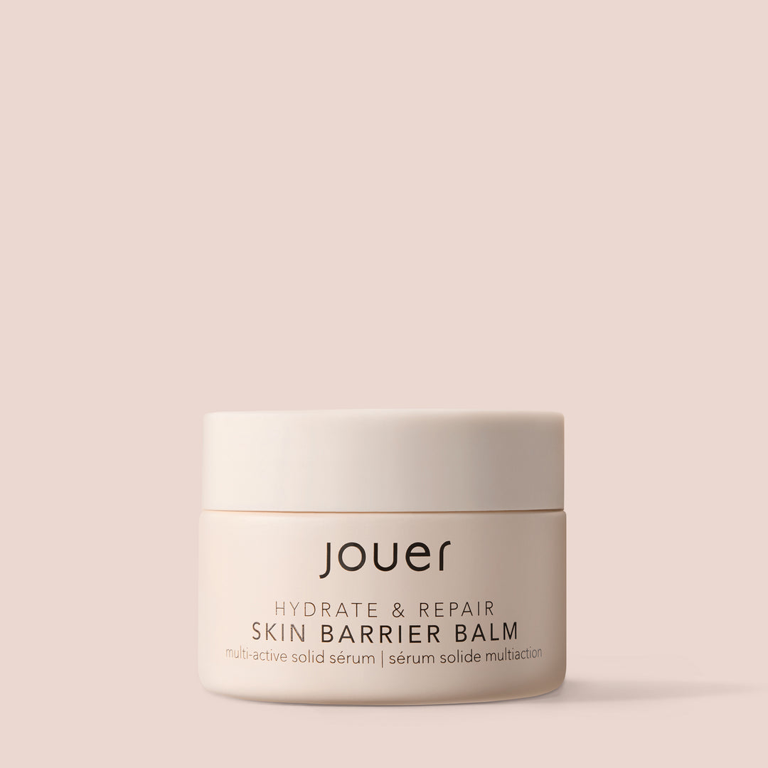 Balm for under eyes in a minimal beige jar labeled "Jouer Hydrate & Repair Skin Barrier Balm" on a soft nude background.