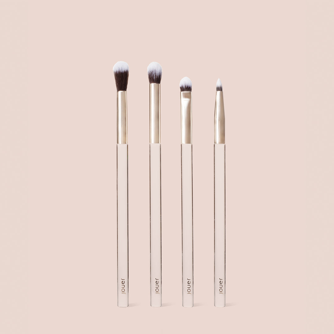 Four eyeshadow brushes from the Make a Wish Brush Set standing upright, featuring soft white-and-brown bristles and gold ferrules