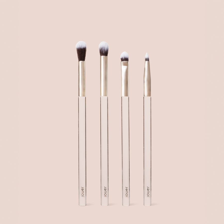 Four Jouer makeup brushes with pink handles arranged by size - liner, eyeshadow, blending, and crease brushes