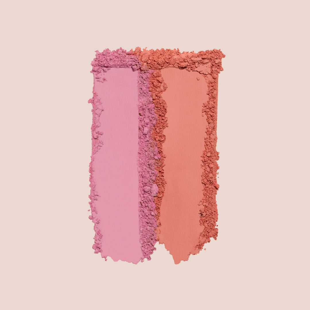 Deux amis, A vertical rectangular swatch of crushed makeup powder, split into two distinct colors. The left side is a soft pink with a slightly rough texture, while the right side is a coral orange, equally rough. This swatch features the Blush Bouquet by Jouer Cosmetics, crafted with a cruelty-free, vegan formula on a solid beige background.