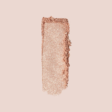  Close-up of a person with short, curly hair who has glowing skin, wearing shimmery eye shadow, glossy lip makeup, and small hoop earrings with a charm. The background is neutral, enhancing the focus on their radiant complexion accentuated by Jouer Cosmetics' Powder Highlighter, which is both vegan and cruelty-free.