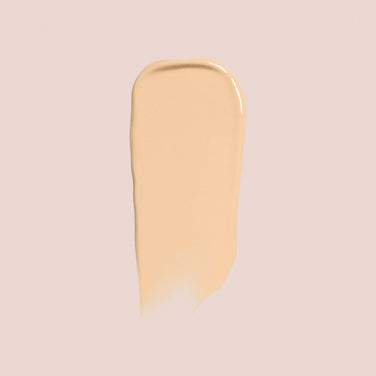  A smooth, beige-colored swatch of Jouer Cosmetics' Essential Crème Foundation is spread on a pale background. The texture appears creamy and even, with the edges of the swatch slightly tapered.