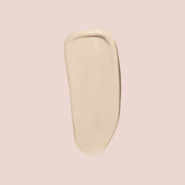  A single swipe of Jouer Cosmetics' Essential Crème Foundation, a creamy, beige-colored makeup product, is displayed against a light pink background. The smooth texture of the foundation ensures flawless coverage without compromising on quality or ethics, thanks to its gluten-free and paraben-free formula.