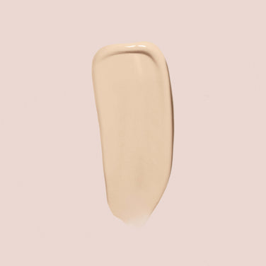  A smooth, beige swipe of Essential Crème Foundation by Jouer Cosmetics on a light beige background. The product has a glossy finish, indicating its liquid or cream consistency. This gluten-free and cruelty-free formula offers both quality and peace of mind for conscious beauty lovers.