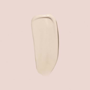  A swatch of Jouer Cosmetics' Essential Crème Foundation, available in a cream-colored shade, is spread smoothly on a light beige background. The texture appears glossy and uniform, resembling a broad brush stroke and is both cruelty-free and paraben-free.