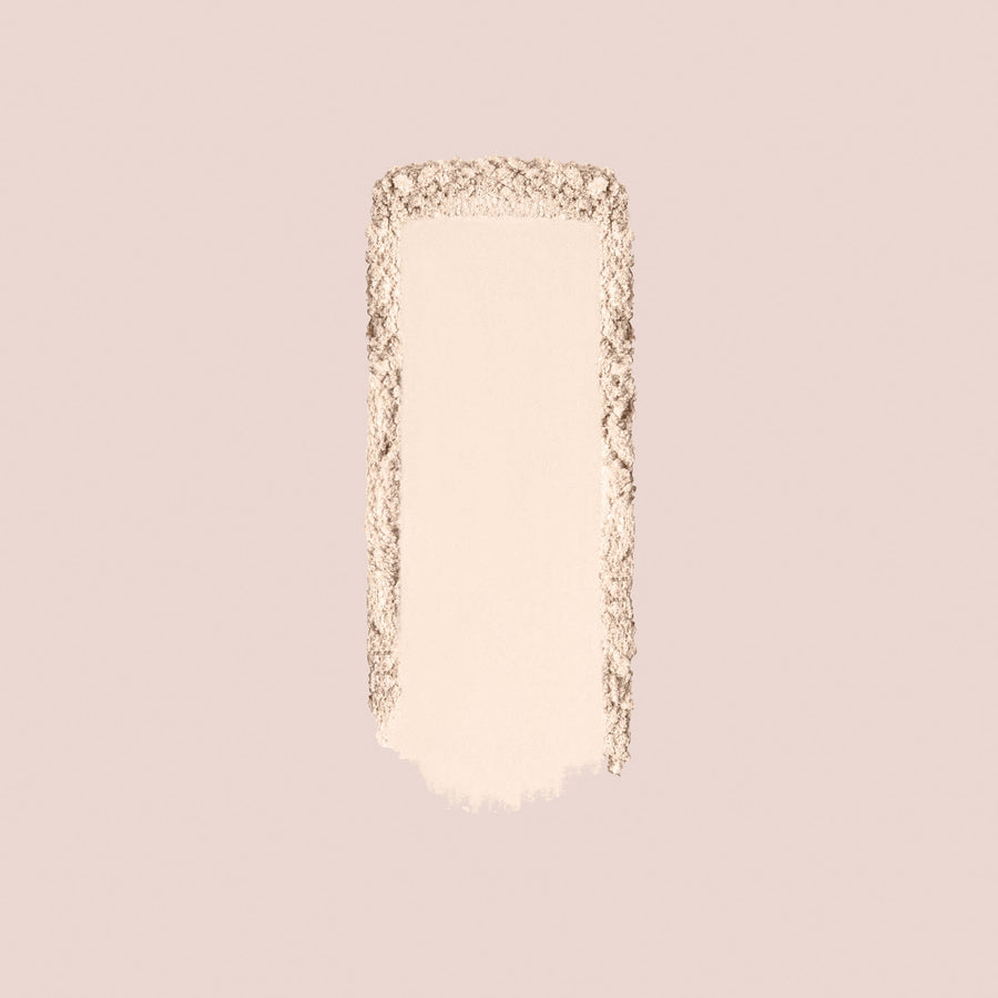 Light beige setting powder swatch with soft edges on pale pink background