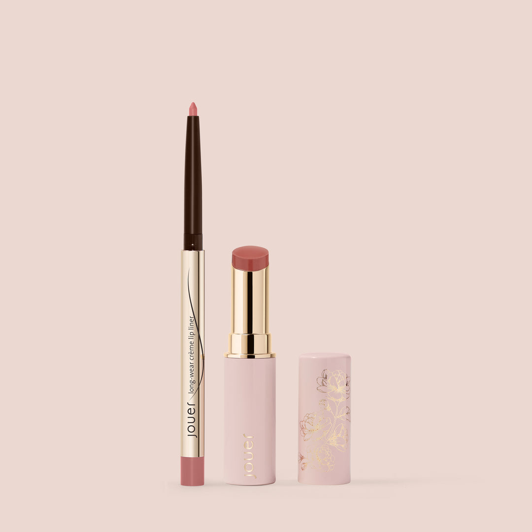 Image of the Bare Rose Lip Kit from Jouer Cosmetics, featuring a pink lip liner pencil and matching pink lipstick set against a light pink background. The cruelty-free lip liner boasts a brown, gold, and pink design, while the lipstick is encased in a pink tube adorned with gold accents and floral patterns.