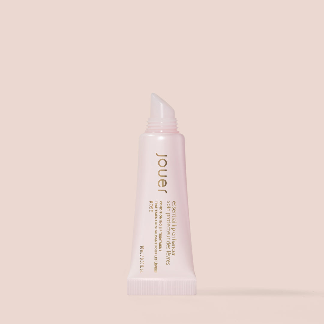 rose, 10 ml alt: A rose-colored tube of Jouer Cosmetics Essential Lip Enhancer, expertly crafted to condition and plump lips. This gluten-free, paraben-free formula is housed in a soft, squeezable tube with a slanted applicator tip, adorned with gold and white text displaying the product name and description.