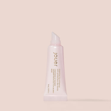  A rose-colored tube of Jouer Cosmetics Essential Lip Enhancer, expertly crafted to condition and plump lips. This gluten-free, paraben-free formula is housed in a soft, squeezable tube with a slanted applicator tip, adorned with gold and white text displaying the product name and description.