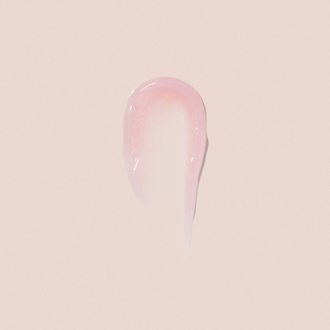 A smooth dab of Jouer Cosmetics' Essential Lip Enhancer is spread on a light beige background, resembling the glossy texture and shiny finish of premium lipstick.