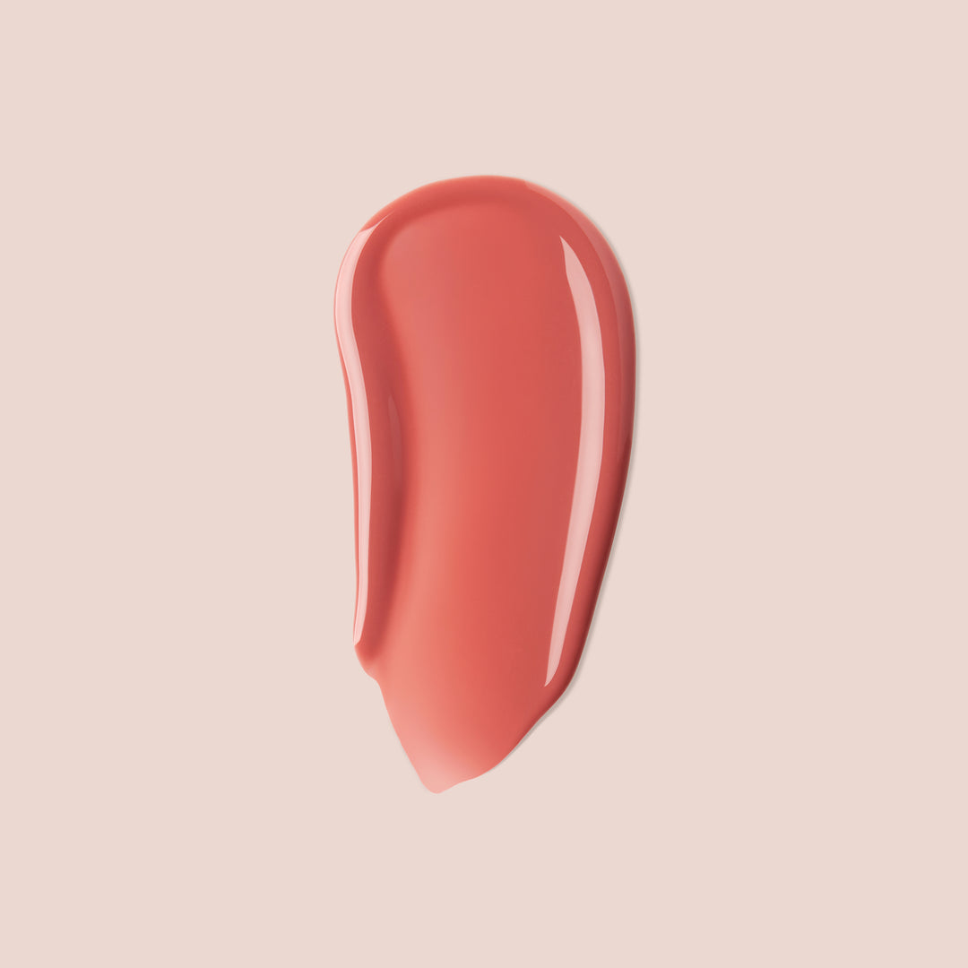 bare rose, A smear of Jouer Cosmetics' Tinted Lip Oil in a peach shade against a light beige background, highlighting its smooth, glossy texture and shiny finish, and free from parabens.
