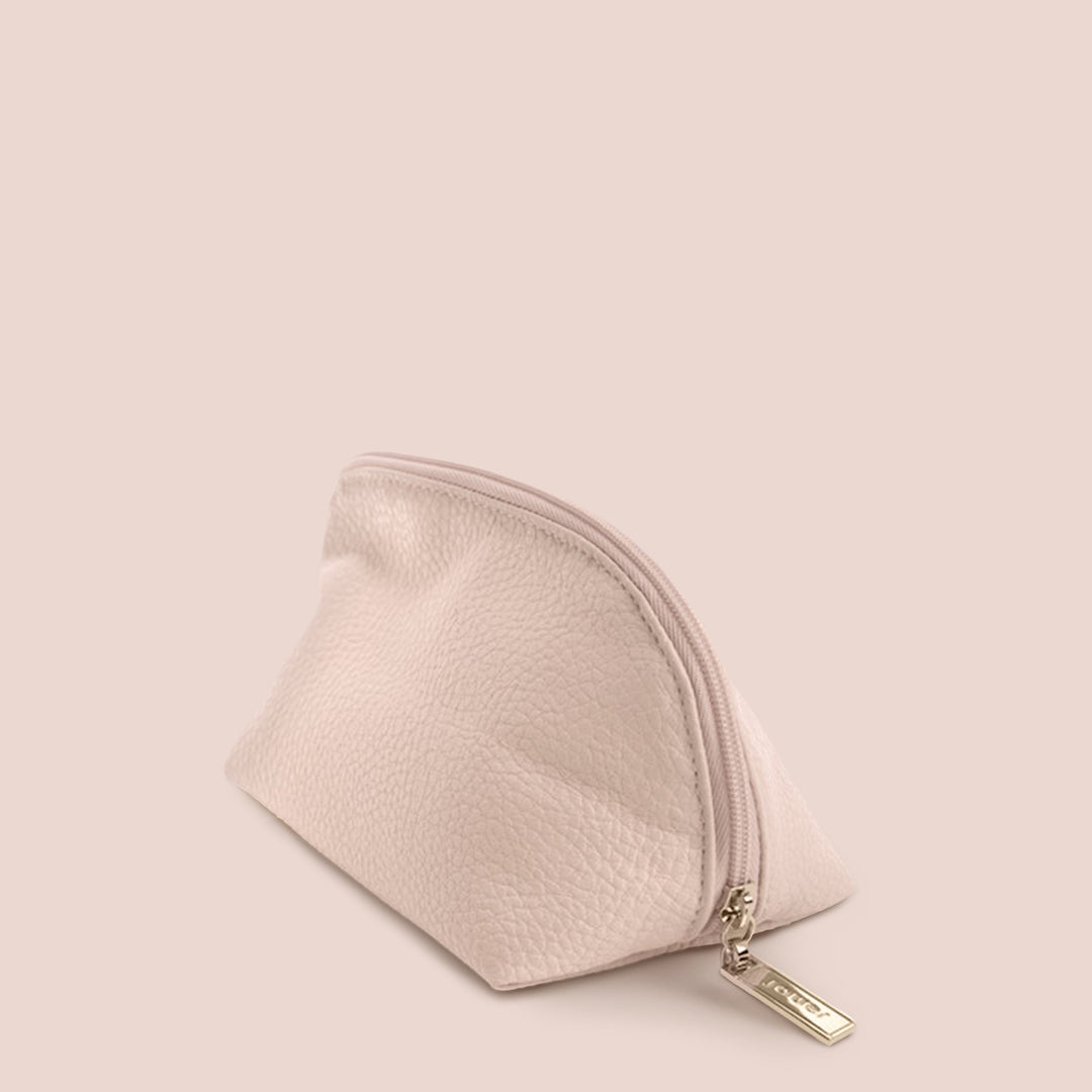 A small, pale pink Pink Makeup Bag with a zip closure, crafted from soft buff leather-like material. The zipper is adorned with a metallic pull-tab engraved with the brand name "Jouer Cosmetics." Travel-friendly and stylish, this pouch is set against a plain, neutral background.