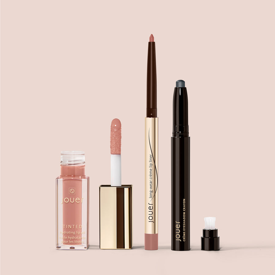 Jouer Le Bardot makeup set kit with tinted lip oil, lip liner, and eyeshadow crayon on pink background