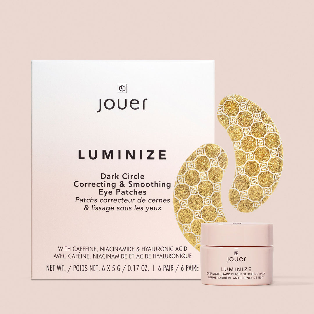 The image showcases the "Luminize Dark Circle Correcting & Smoothing Eye Patches" set from Jouer Cosmetics. This vegan skincare collection includes a box containing six pairs of gold-patterned eye patches and a small jar of accompanying product with its label displayed, making it perfect to elevate your slugging balm routine.