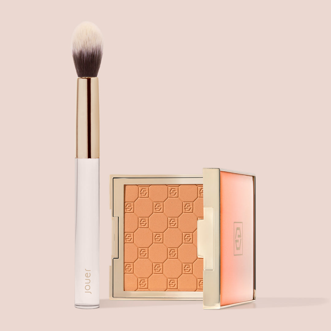 Jouer Precision Brightening Set in Orange with a warm copper-toned embossed powder compact and Jouer tapered brush.