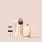 Jouer Les Must-Haves makeup set with lipstick, foundation, highlighter and brush on pink background
