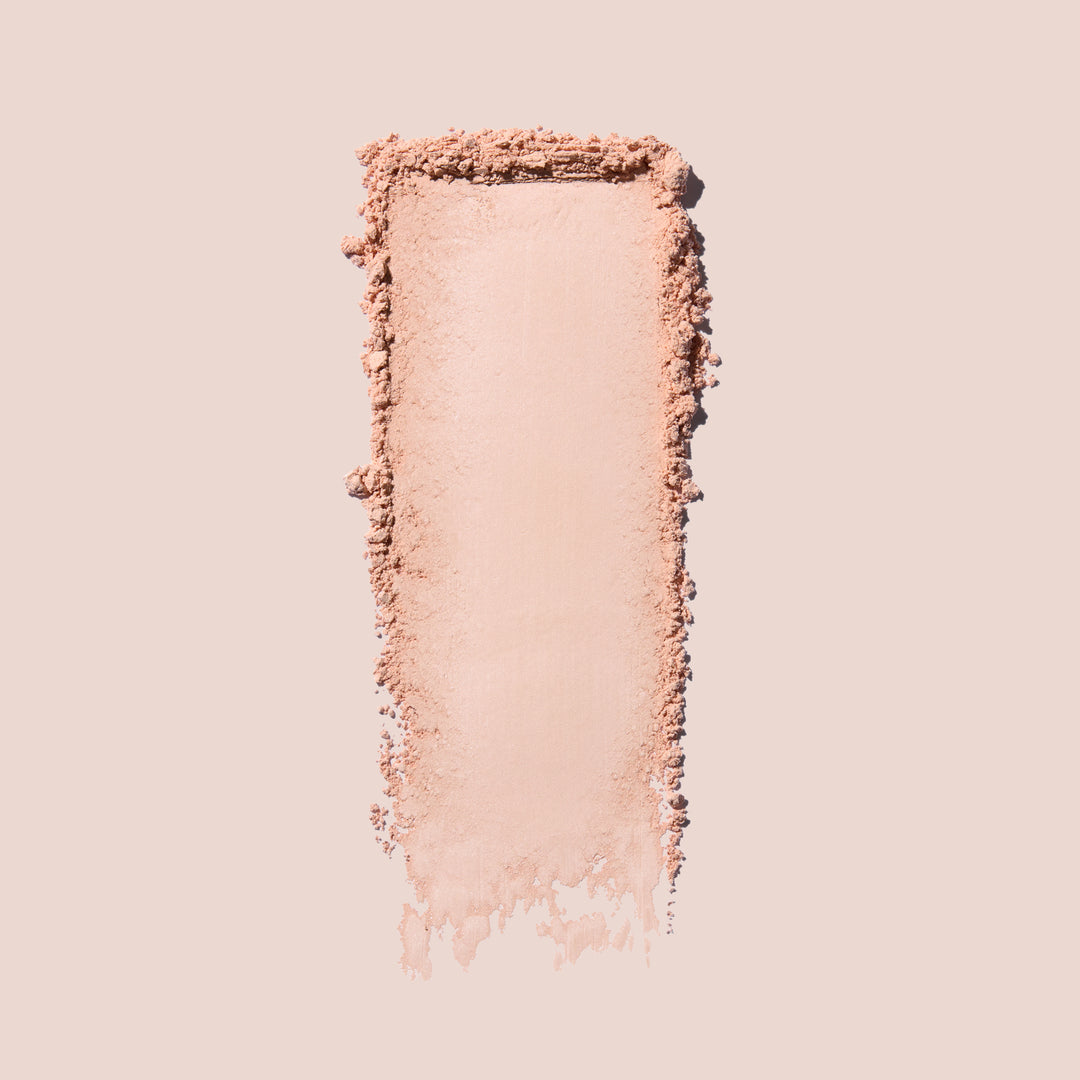 Jouer Brightening Powder swatch in light pink showing the silky, finely milled texture on a beige background.