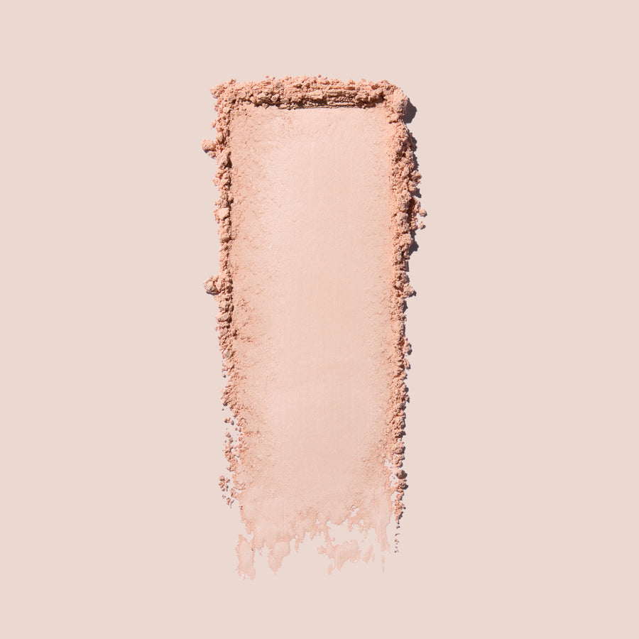 Jouer Brightening Powder swatch in light pink showing the silky, finely milled texture on a beige background.