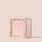 Jouer Brightening Powder open compact in pink with embossed logo pattern on a beige background.