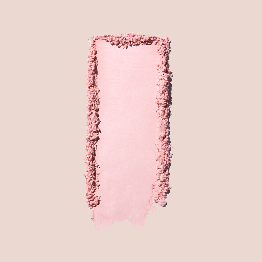Jouer Brightening Powder swatch in cool pink showing the smooth, crumbled powder texture on a beige background.