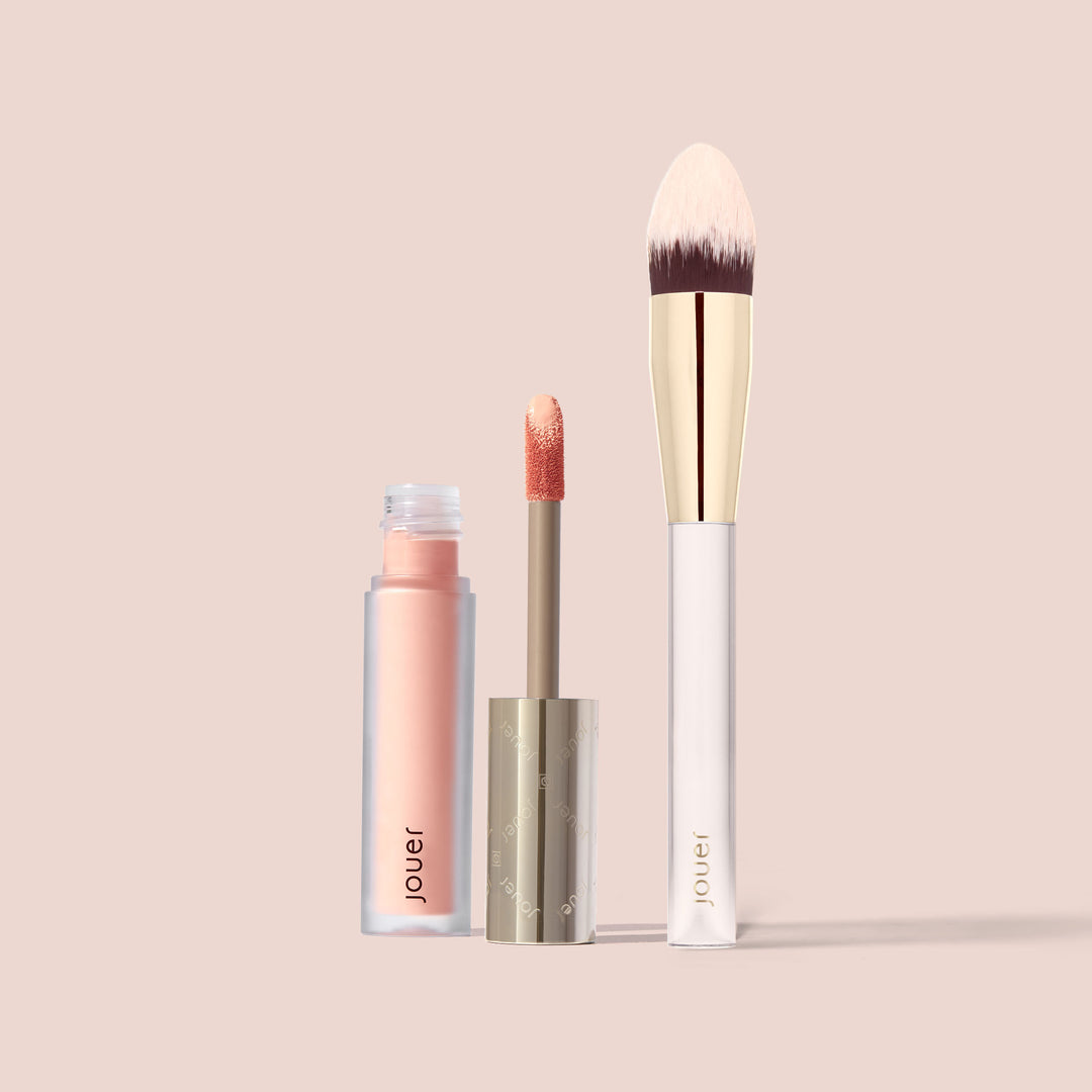 Jouer Light Bright Brightening Under-Eye Corrector shown open with doe-foot applicator alongside a white and gold concealer brush.