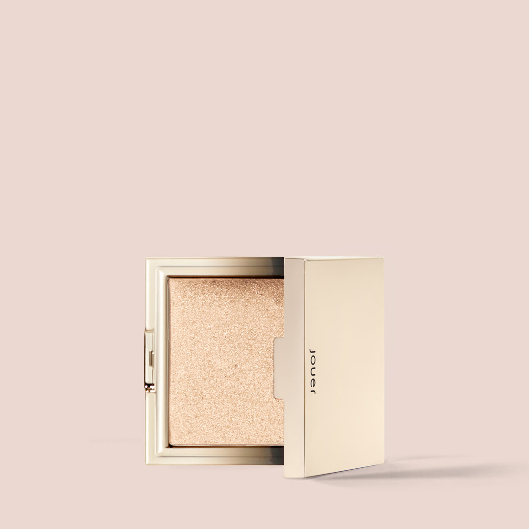 Citrine, full size alt: A compact Powder Highlighter with a shimmery golden champagne hue in an open gold case is displayed against a beige background. The sleek case, branded subtly with "Jouer Cosmetics" on the lid, houses a vegan formula that is both paraben-free and cruelty-free.