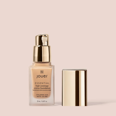  A 20 ml (0.68 fl. oz.) bottle of Essential Crème Foundation by Jouer Cosmetics, featuring a gold pump dispenser and a matching cap beside it. The foundation bottle displays "Hyaluronic Acid, Matte + Oil Free" and is noted for being Cruelty Free and Paraben Free.