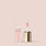 deluxe mini  alt: An open tube of Essential Lip Oil from Jouer Cosmetics, featuring a golden lid, is displayed against a plain beige background. The vegan lip oil contains pink-tinted liquid, and the applicator wand has a soft pink sponge tip. The transparent, square-shaped packaging showcases the luxurious product within.